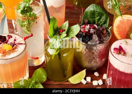 Cocktails colorés dans différents verres sur une table en bois Banque D'Images