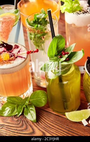 Cocktails colorés dans différents verres sur une table en bois Banque D'Images