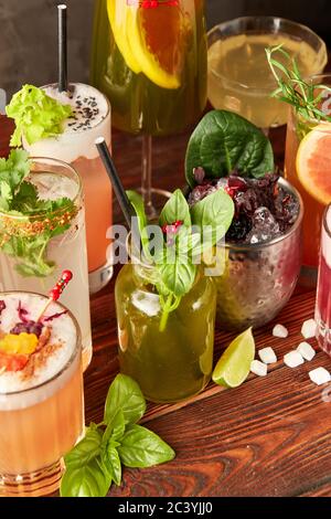 Cocktails colorés dans différents verres sur une table en bois Banque D'Images