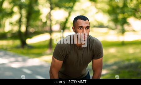 Homme noir millénaire sur la piste de jogging au parc, se reposant après son entraînement du matin Banque D'Images