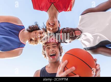 Divers joueurs de basket-ball se rassemblent et font des visages stupides, s'amusant avant le match. Vue de dessous Banque D'Images