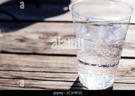 un verre d'eau à l'eau étincelante est sur une table en bois avec de petites bulles venant du fond Banque D'Images