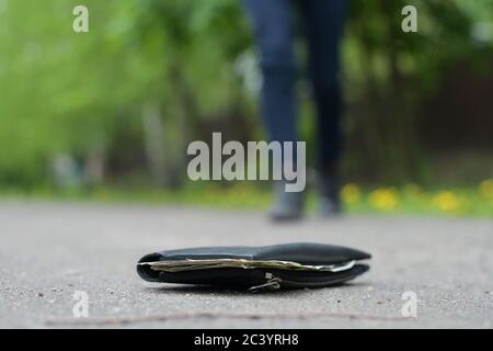 l'homme va au portefeuille, qui se trouve sur le chemin de l'asphalte dans le parc Banque D'Images