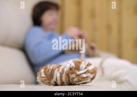 une boule de fil se trouve à côté de la femme qui tricots une écharpe Banque D'Images