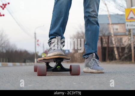 adolescent très proche de l'appareil photo sur un skateboard, gros plan des jambes Banque D'Images