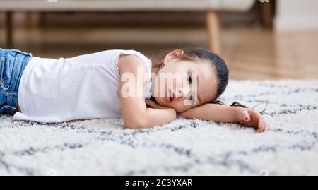 Ennui. Alamed Asian Girl couché sur le sol à la maison, Panorama Banque D'Images