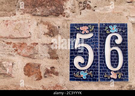 Numéro 56 sur le mur de briques brunes d'une maison dans le centre historique d'une ville italienne Banque D'Images