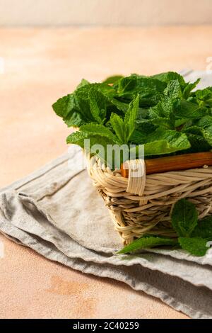 des branches de menthe verte fraîche dans un panier en osier sur fond clair Banque D'Images