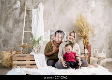 Les familles asiatiques posent sourire assis sur la moquette tout en regardant la caméra Banque D'Images