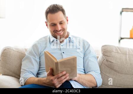Un gars sympa lisant un livre à la maison Banque D'Images