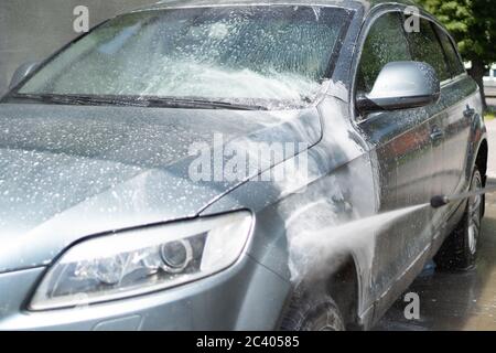 Lavage complet de voiture au libre-service. Gouttes d'eau éclaboussé par un pulvérisateur qui lave la voiture. Pare-brise. Mousse blanche Banque D'Images