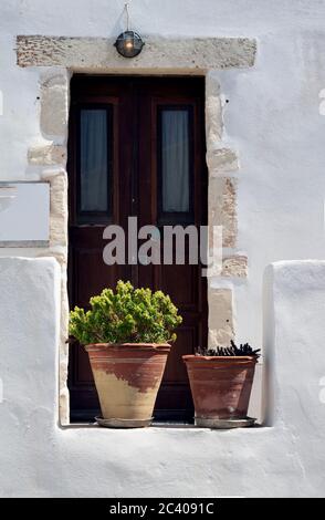 Grèce, l'île de Sikinos. Une porte d'entrée à une maison de village. Plantes ornementales en pots de terre cuite au premier plan. Maçonnerie simple mais élégante. Banque D'Images