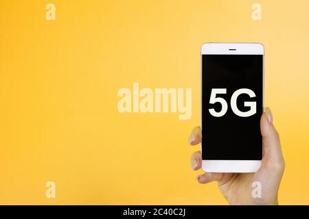 Arrière-plan créatif, main tenant un téléphone avec un symbole 5G. Le concept de réseau 5G, Internet mobile haut débit, réseaux de nouvelle génération Banque D'Images