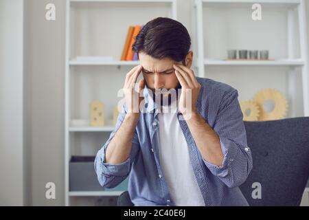 Jeune homme avec maux de tête ou hypertension à la maison. Banque D'Images
