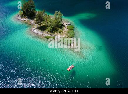 23 juin 2020, Bavière, Grainau: Les excursions prennent un pédalo sur l'Eibsee, chatoyant dans différentes nuances de bleu, au-delà de petites îles (vue aérienne avec un drone). Photo: Sven Hoppe/dpa Banque D'Images