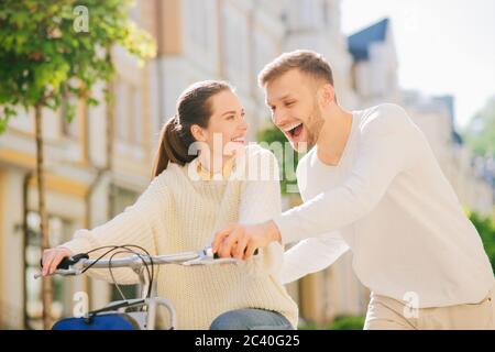 Homme enseignant une femme joyeuse à vélo Banque D'Images