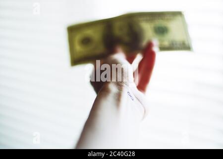 Tatouage infini sur le poignet. Facture de dollar floue à la main sur fond blanc brillant Banque D'Images