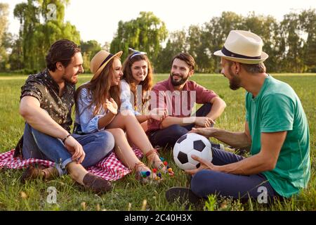 Groupe d'amis ayant fait une pause après avoir joué au football en plein air. Les jeunes communiquent à la campagne le jour de l'été Banque D'Images