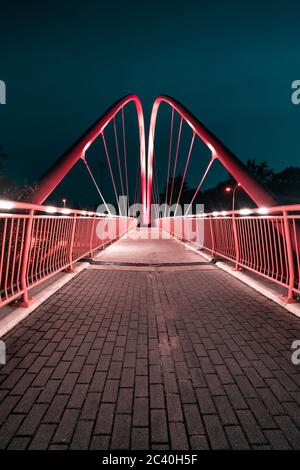 Bydgoszcz la nuit. La célèbre passerelle à vélo au-dessus de la route de l'université dans la nuit lumières de la ville. Banque D'Images