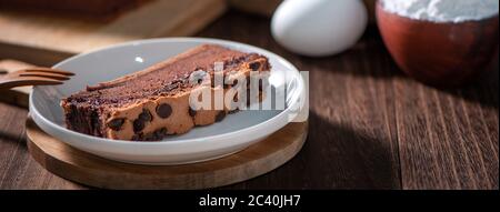 Gâteau éponge traditionnel taïwanais au goût de chocolat (taïwanais castella kasutera) sur une table de fond en plateau de bois avec les ingrédients, gros plan. Banque D'Images