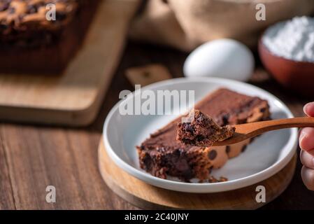 Gâteau éponge traditionnel taïwanais au goût de chocolat (taïwanais castella kasutera) sur une table de fond en plateau de bois avec les ingrédients, gros plan. Banque D'Images
