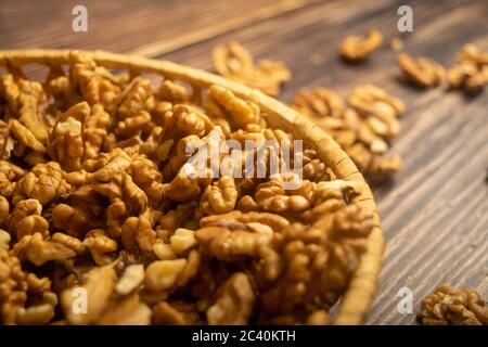 Noix pelées dans un panier en osier et noix pelées éparpillées sur une table en bois. Une alimentation saine. Régime de remise en forme. Gros plan Banque D'Images