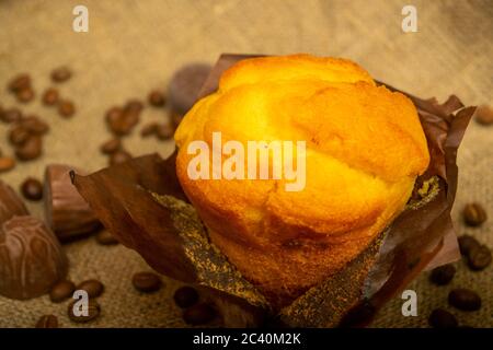 Délicieux cupcake frais, grains de café et chocolat sur un tissu rugueux. Gros plan Banque D'Images