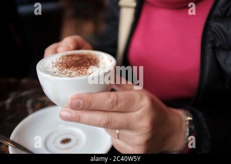 Gros plan d'une femme qui apprécie une tasse de cappuccino dans un café Banque D'Images