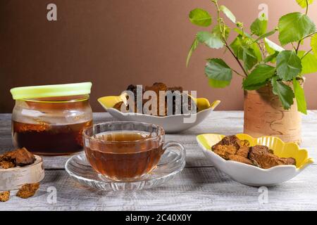 Infusion curative de chaga aux champignons de bouleau, ingrédients pour sa cuisine, brindilles de bouleau sur table en bois. Café ou thé de chaga. Boissons améliorant l'immunité Banque D'Images