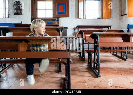 Petit garçon assis dans le bureau dans l'école d'époque Banque D'Images