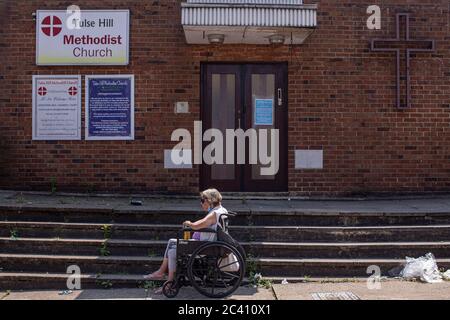 Londres, Angleterre. 23 juin 2020. Une dame âgée en fauteuil roulant tenant une grande capacité d'attente devant l'église méthodiste Tulse Hill dans le sud de Londres, en Angleterre. (Photo de Sam Mellish / Alamy Live News) Banque D'Images