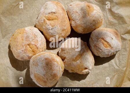 Petits pains au levain faits maison. Petits pains faits main sur papier de cuisson. Juste à l'extérieur du four et encore chaud. Banque D'Images