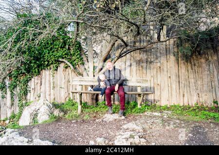 Père et petit fils assis sur le banc en bois dans le parc Banque D'Images