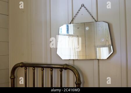 Un miroir ancien suspendu au-dessus d'un vieux lit dans la chambre Jack London au Wolf Creek Inn à Wolf Creek, Oregon, États-Unis. Banque D'Images