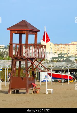 Tour de maître-nageur sur une plage vide avec un drapeau rouge levé. Un panneau interdisant la natation dans une mer. Banque D'Images