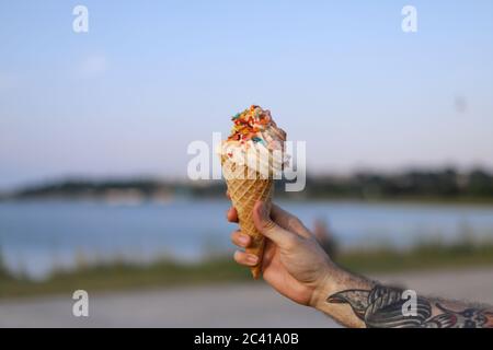 La main d'un homme tient une grande glace à gaufre crème saupoudrée Banque D'Images