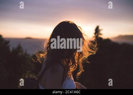 jeune femme aux cheveux ondulés au coucher du soleil Banque D'Images