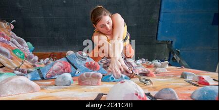 Femme grimpant au mur d'escalade intérieur Banque D'Images