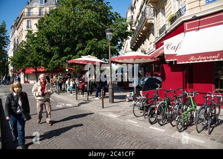 Paris, France - 15 mai 2020 : scène urbaine à l'Ile Saint-Louis. Les personnes âgées dans les masques protecteurs marchent; les gens achètent la célèbre glace Berthillon prendre awa Banque D'Images