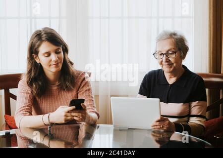 petite-fille utilisant un mobile et grand-mère utilisant une tablette Banque D'Images