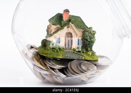 Concept propriétaire. Maison miniature à l'intérieur d'un pot plein de pièces Banque D'Images