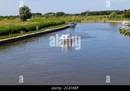 Un couple dans un petit bateau de plaisance faisant place vers le pont Ludham sur la rivière Ant sur les Norfolk Broads à Ludham, Norfolk, Angleterre, Royaume-Uni. Banque D'Images