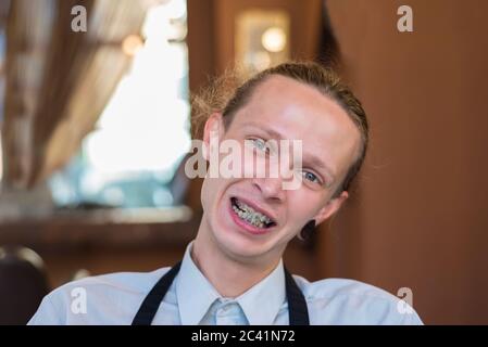 Portrait d'un homme de vingt-cinq ans avec des bretelles sur ses dents, souriant. Mauvaise morsure chez un jeune homme souriant. Pathologie dentaire, correction de Banque D'Images