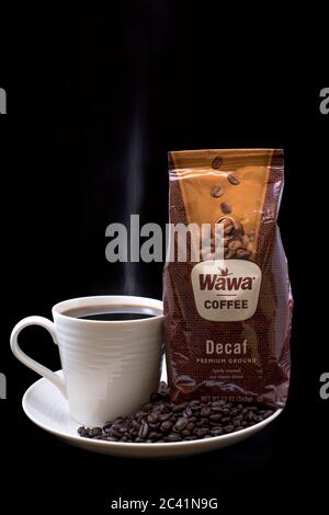 Sac de café Wawa décaféiné gros plan avec une tasse de café Wawa brassé, une tasse blanche sur une assiette blanche, des grains de café et un fond noir Uni Banque D'Images