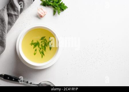 Bouillon de poulet avec oignon vert dans un bol blanc sur table blanche. Copier l'espace. Vue de dessus. Banque D'Images