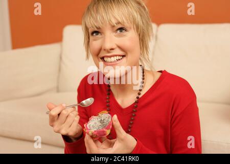 La jeune femme mange un fruit dragon Banque D'Images