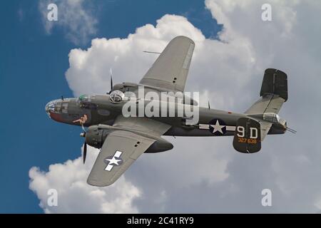 Un bombardier B-25 « Pitchell » vole à travers des nuages spectaculaires et un ciel bleu foncé. Banque D'Images