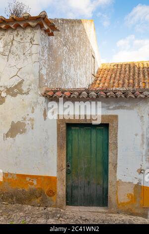 Entrée extérieure du bâtiment ancien en stuc blanc avec verdure porte à panneaux et toit en terre cuite dans un ciel bleu ciel nuageux Banque D'Images