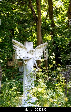 Croix décorée avec une sculpture d'ange au cimetière d'Abney Park, Londres, Royaume-Uni Banque D'Images