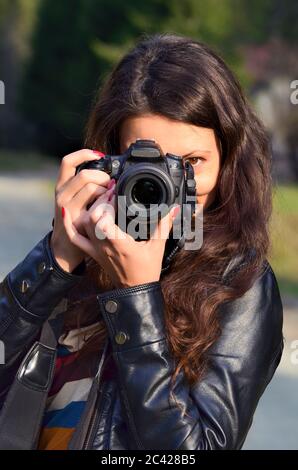 Portrait d'une jeune femme photographe utilisant un appareil photo reflex numérique dans la nature, orientation verticale Banque D'Images